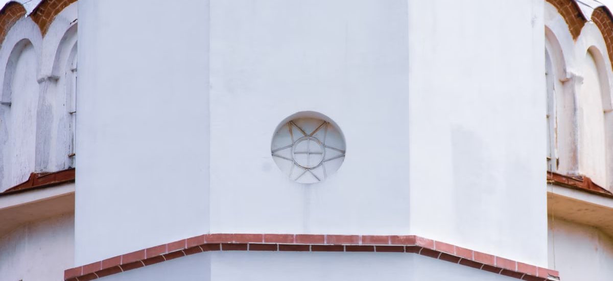 Close-up view of a white church dome exterior with intricate architectural designs and red accents.