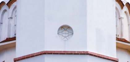 Close-up view of a white church dome exterior with intricate architectural designs and red accents.
