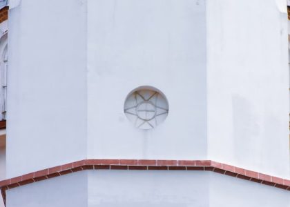 Close-up view of a white church dome exterior with intricate architectural designs and red accents.